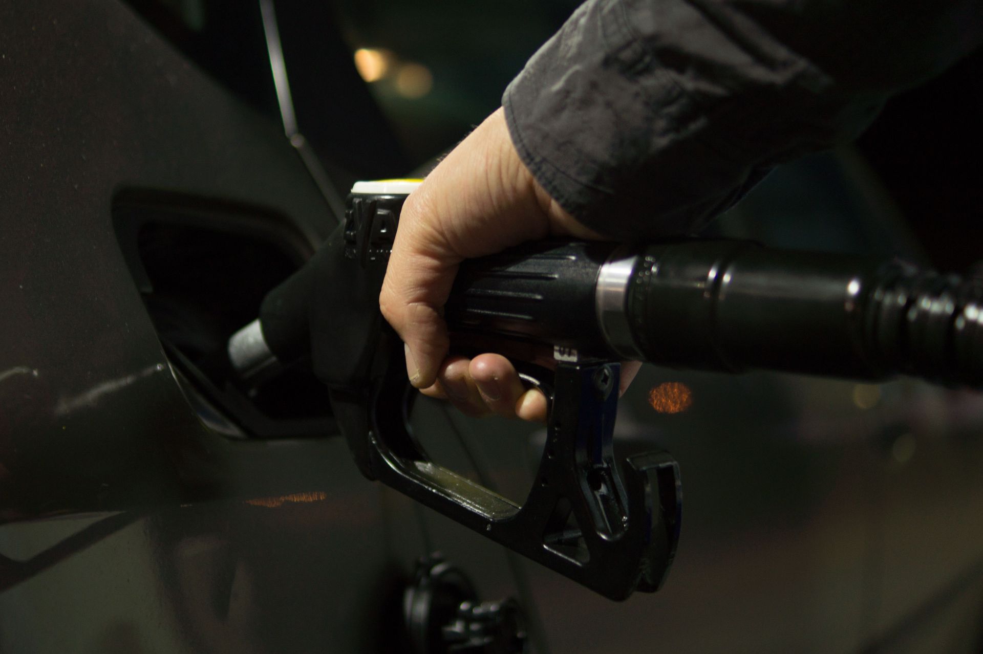 Close-up of a person refueling a car at a gas pump during night.